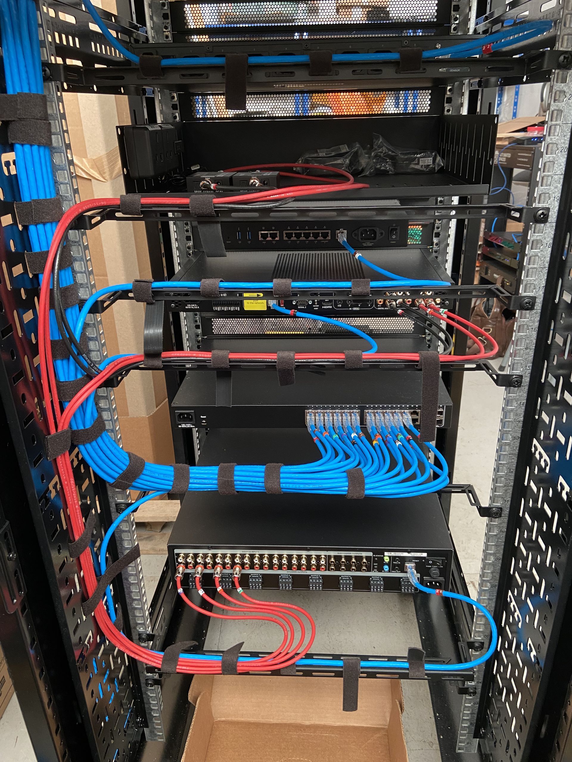 Network server rack with blue and red cables, black hardware, and cable management straps.