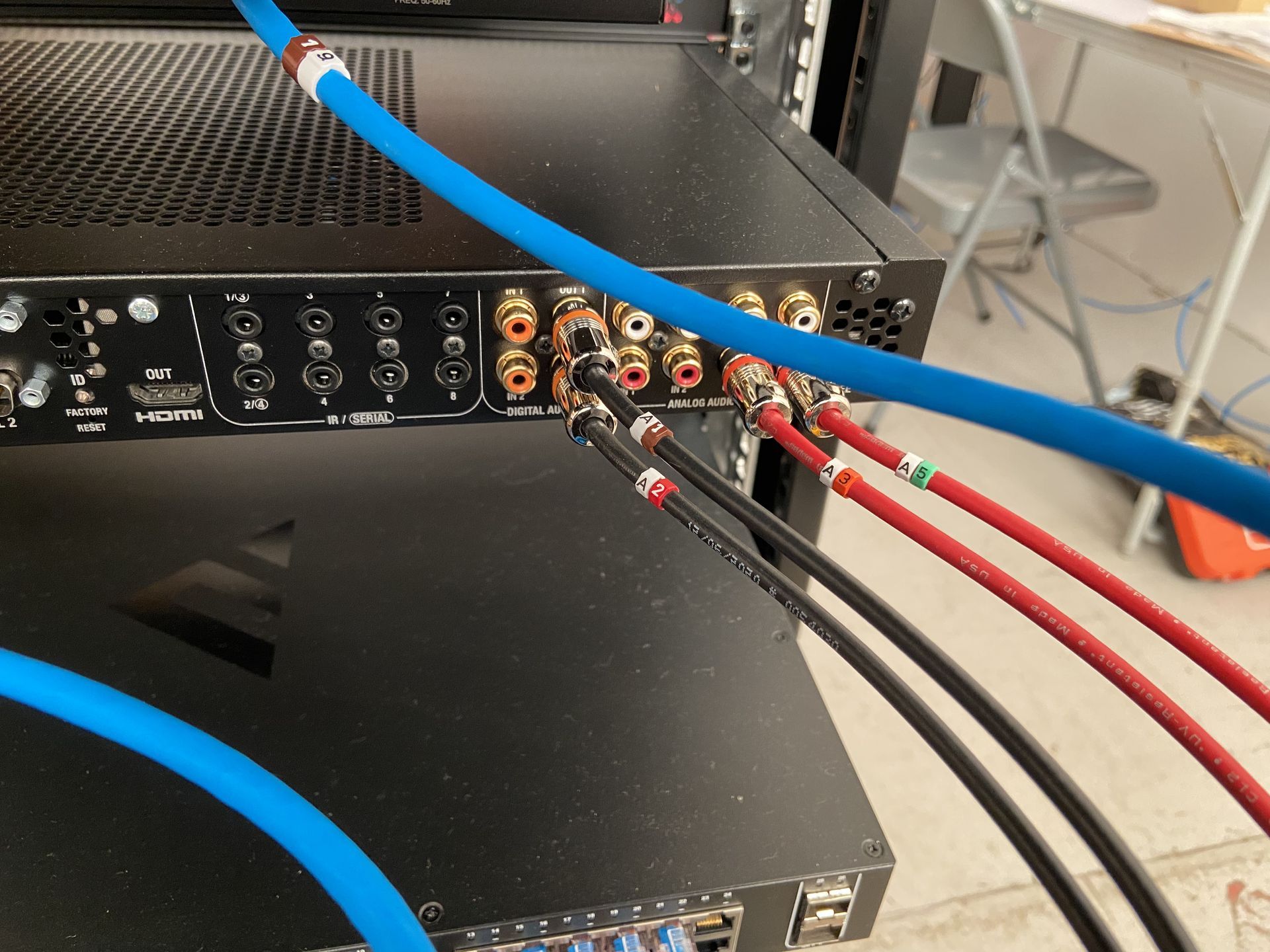 Black audio equipment rack with blue, red, and black cables connected to the back.