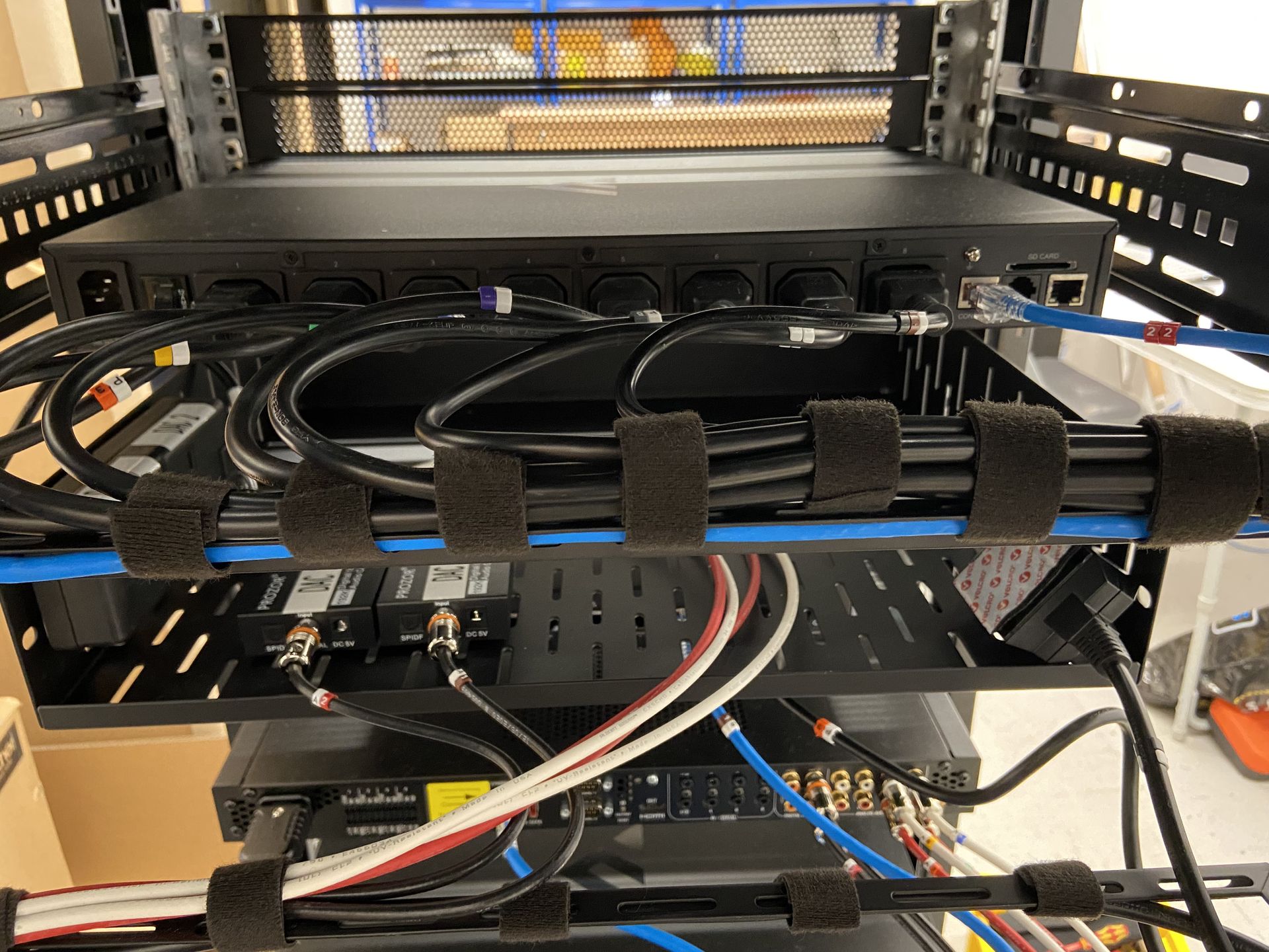 Rack-mounted equipment with power distribution, cables, and cable management straps in a server room.