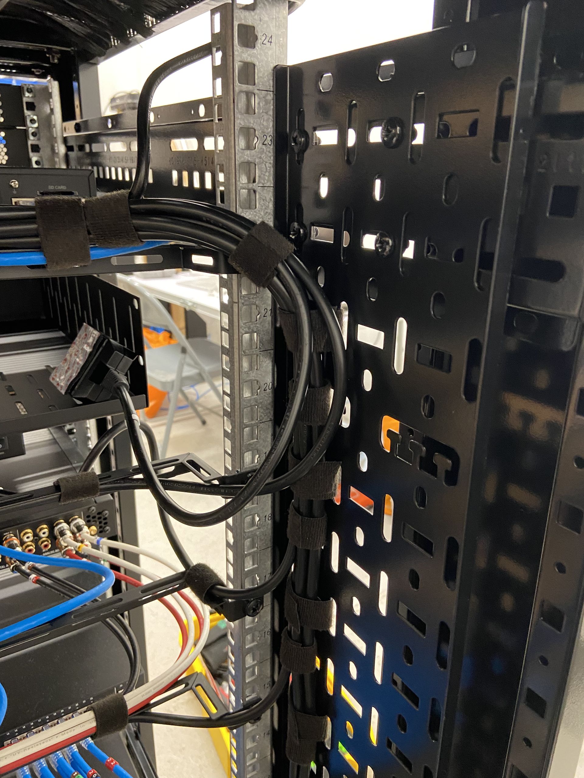 Black cables secured with velcro straps along a metal rack in a server room.