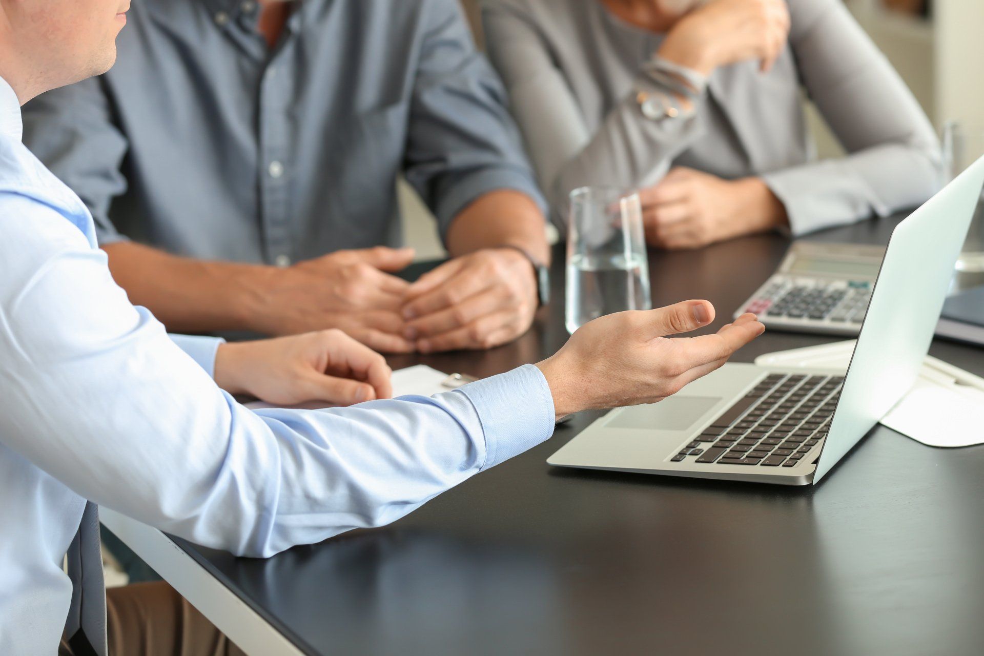 People in a meeting discussing ideas around a laptop at a conference table
