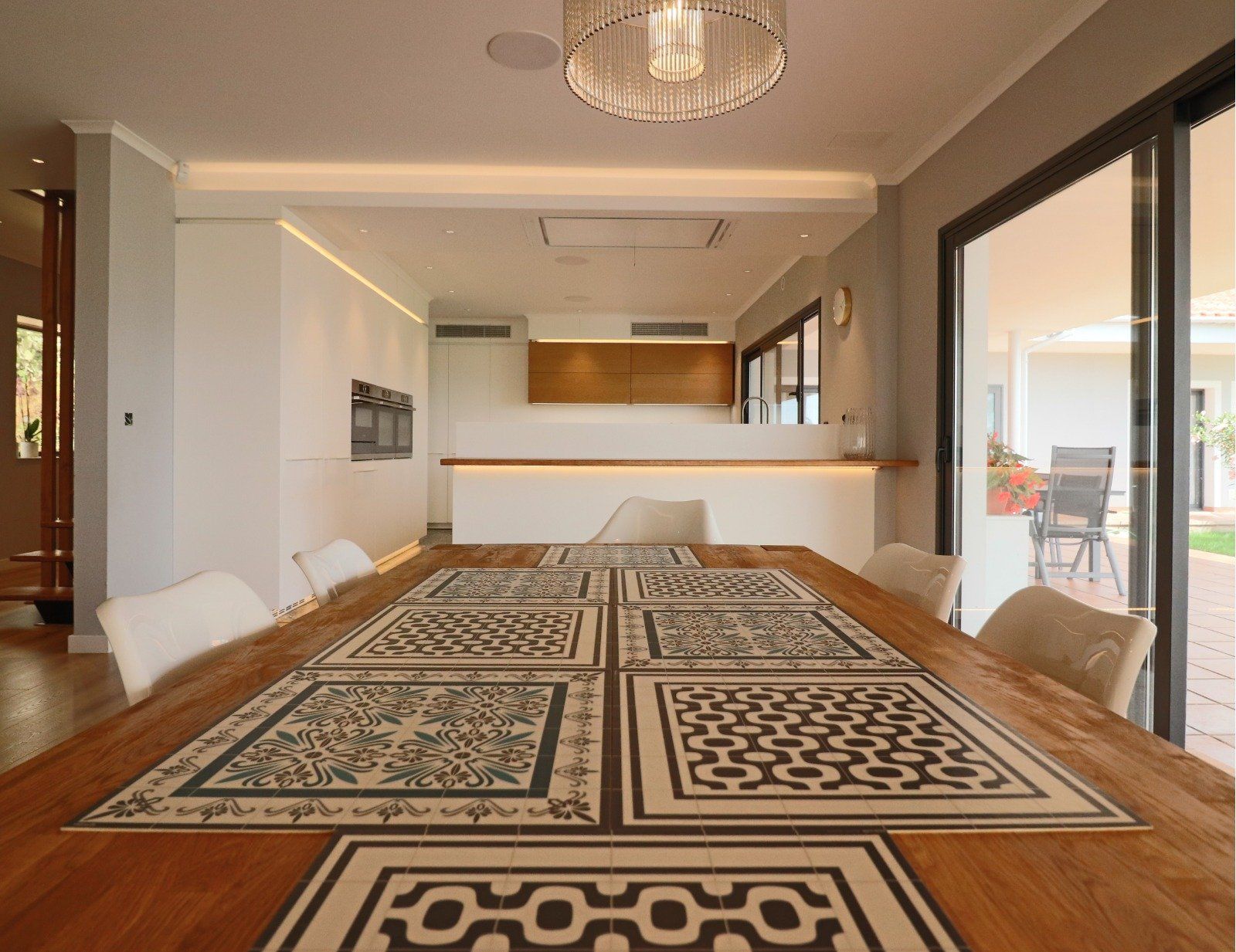 Dining room with long wooden table, place mats, chairs, and open to a patio.