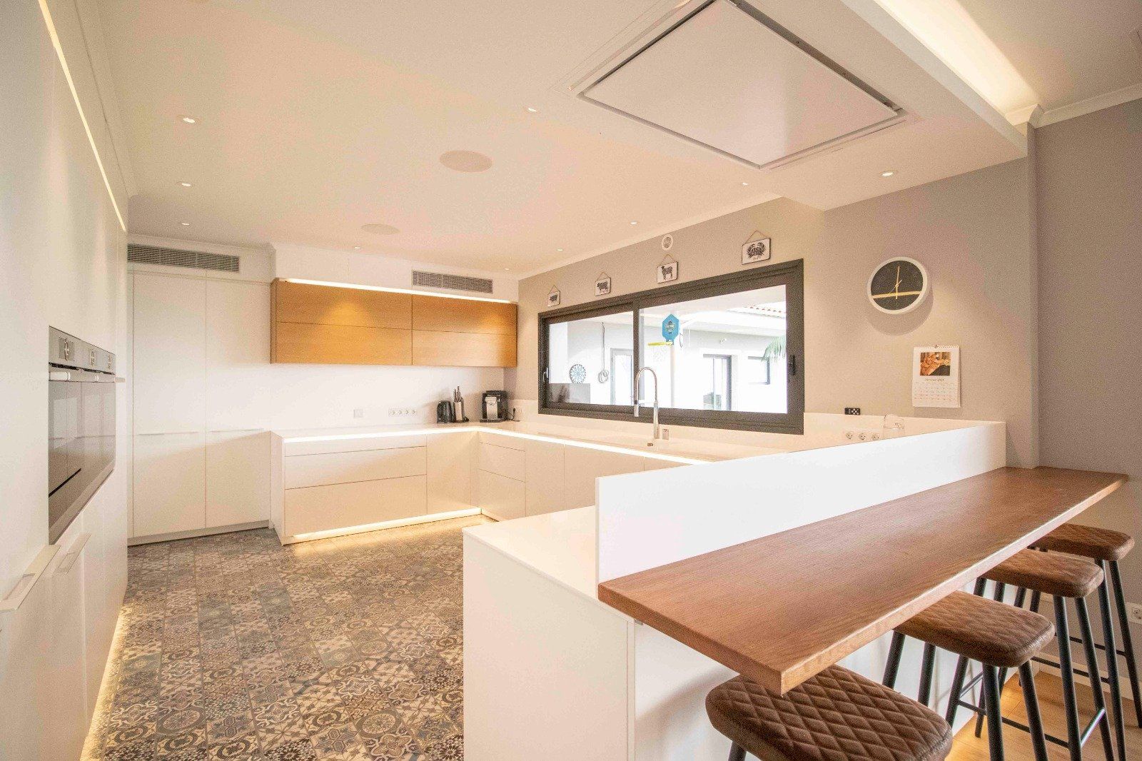 Modern kitchen with white cabinets, wood countertops, and a breakfast bar with stools.