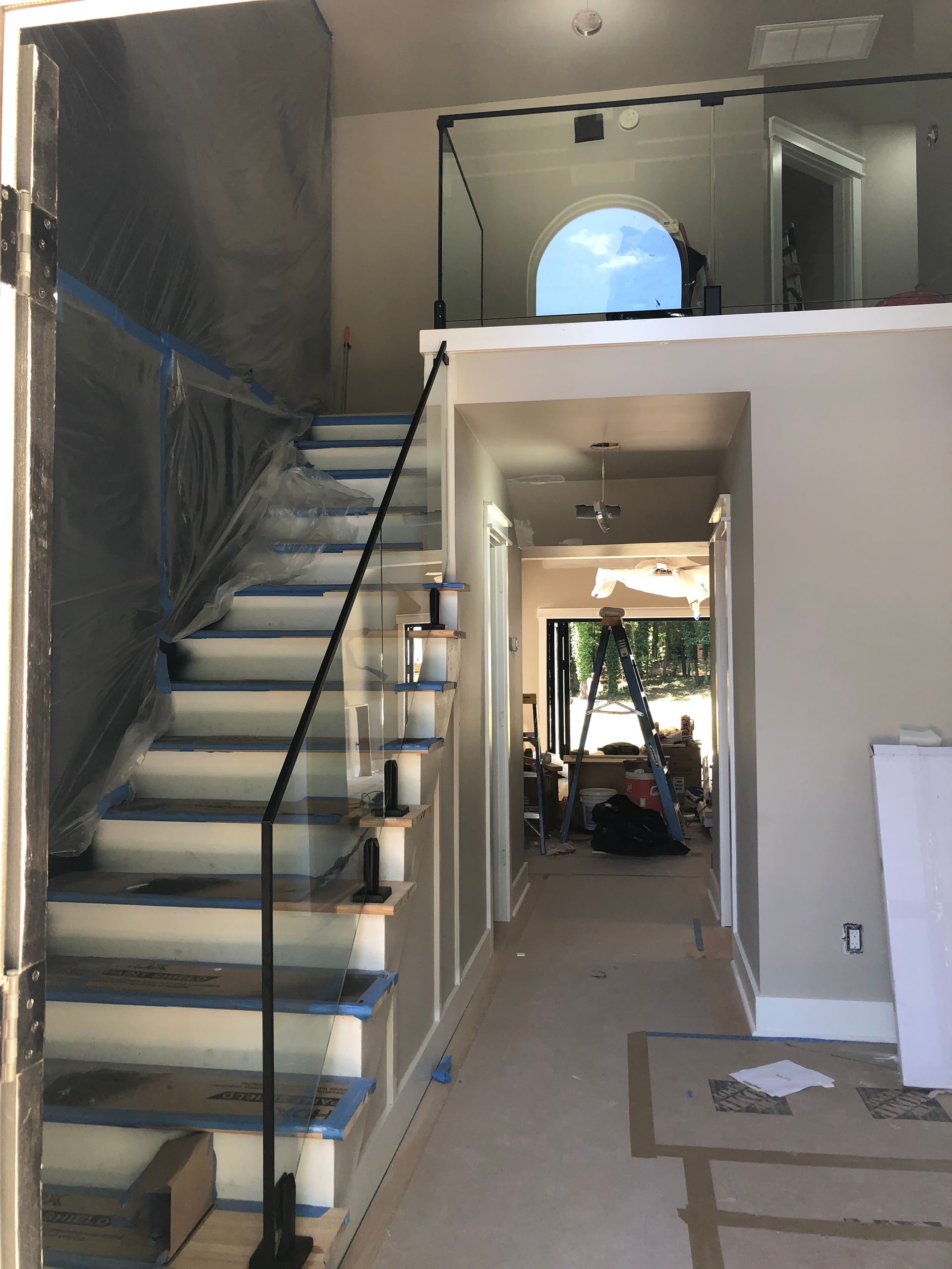 Interior stairwell with blue steps, white walls, and a hallway leading to a bright windowed room.