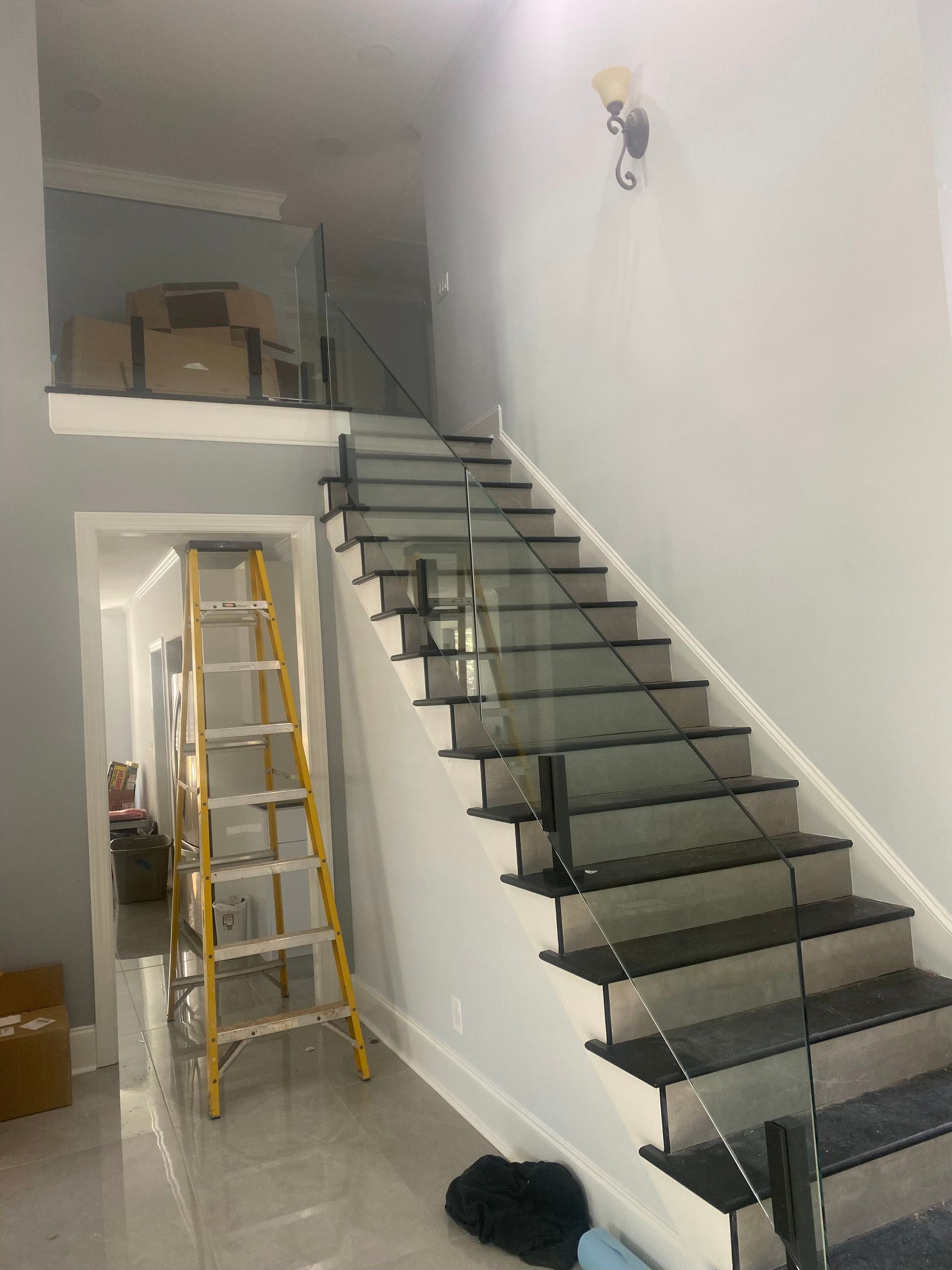 Interior stairwell with a black staircase, ladder, and storage loft above.