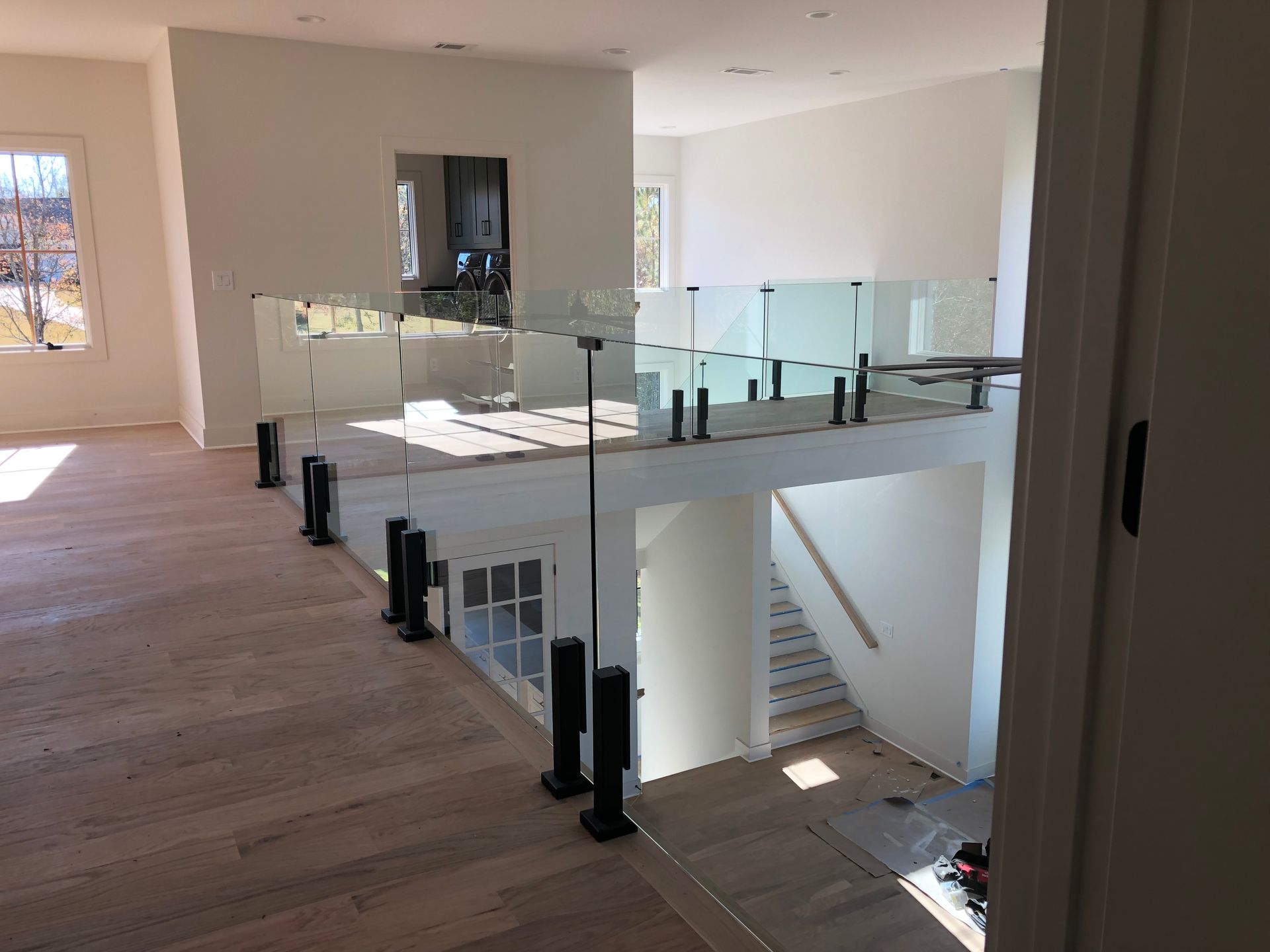 Modern interior landing with glass railing, stairs, and large windows