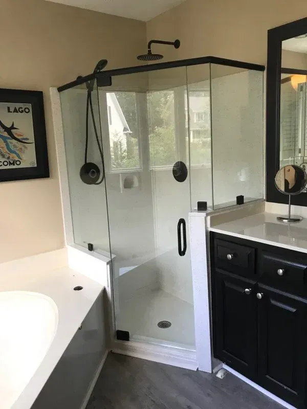 Modern bathroom with glass shower, black fixtures, and a white vanity with a black cabinet.