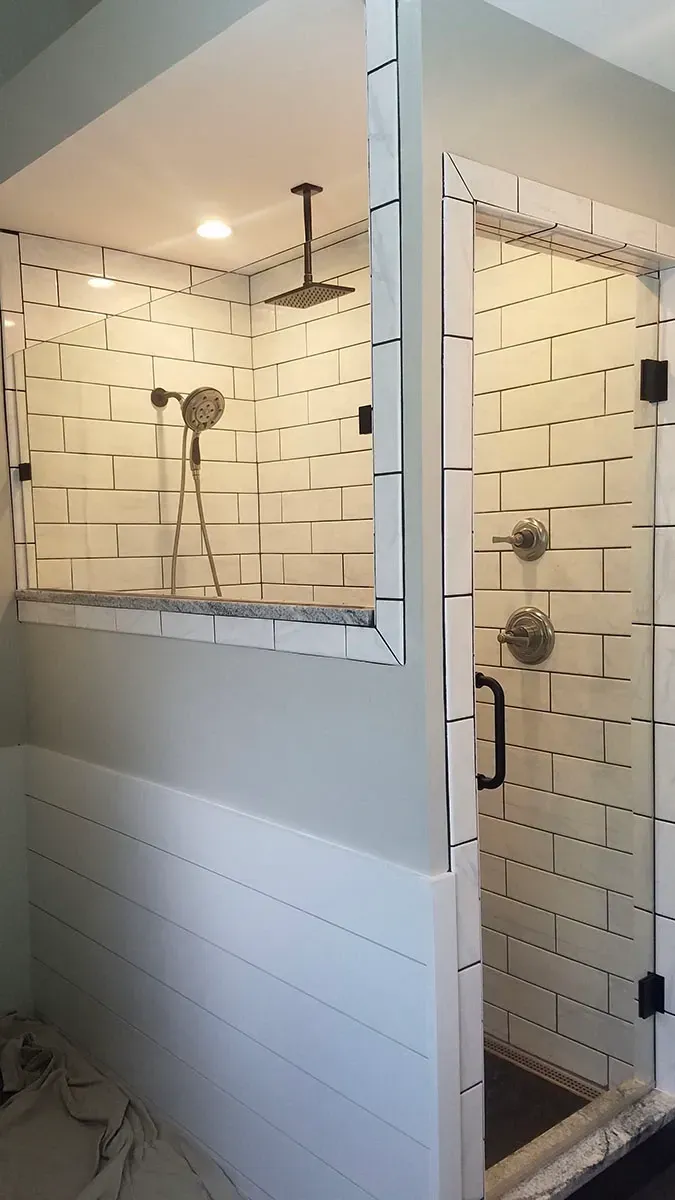 Modern bathroom with a tiled shower, glass doors, and a rain shower head.