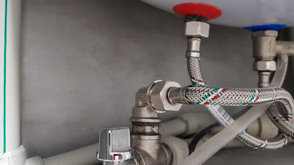 A Water Heater With A Hose Attached To It — DAVMAC Plumbing in Wauchope, NSW
