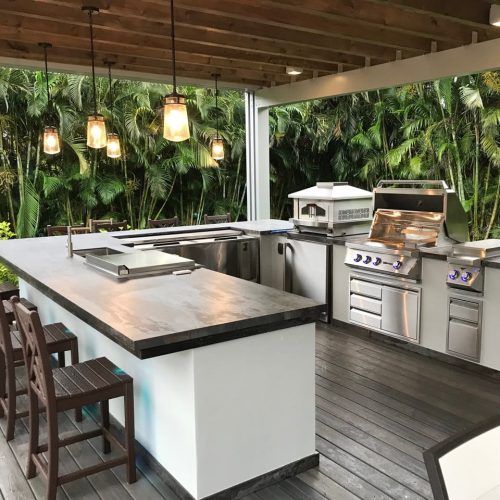 Outdoor kitchen with stainless steel appliances, concrete countertop, and wood deck.