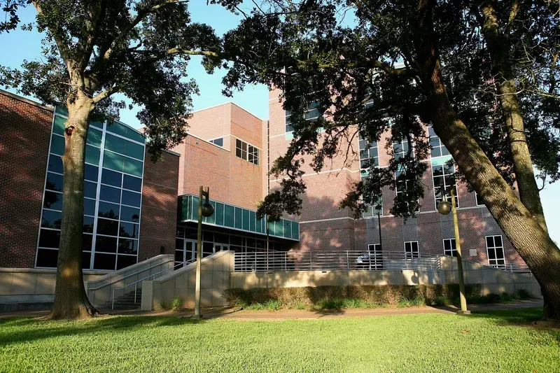 A large brick building with a lot of windows and trees in front of it
