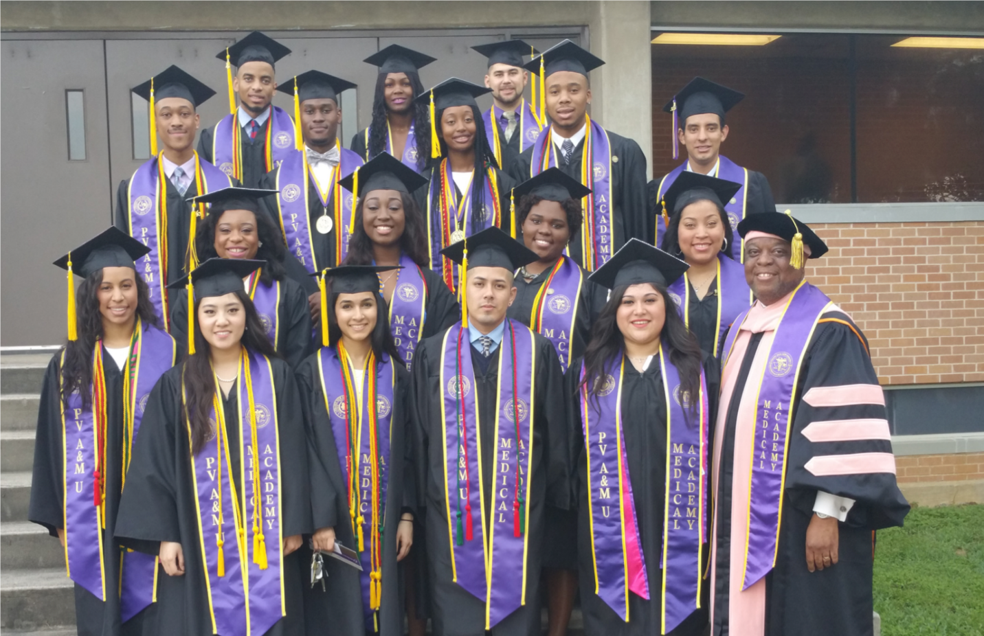 A group of graduates are posing for a picture in front of a building.
