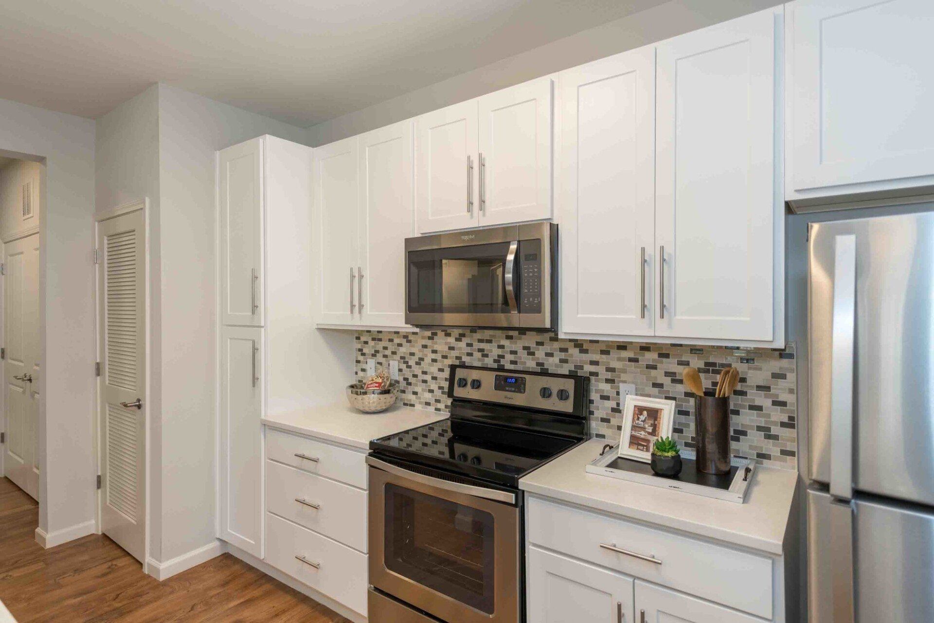 Modern kitchen with white cabinets, stainless steel appliances, and a mosaic backsplash at Silver Collection at Celebrate apartment community in Fredericksburg, VA.