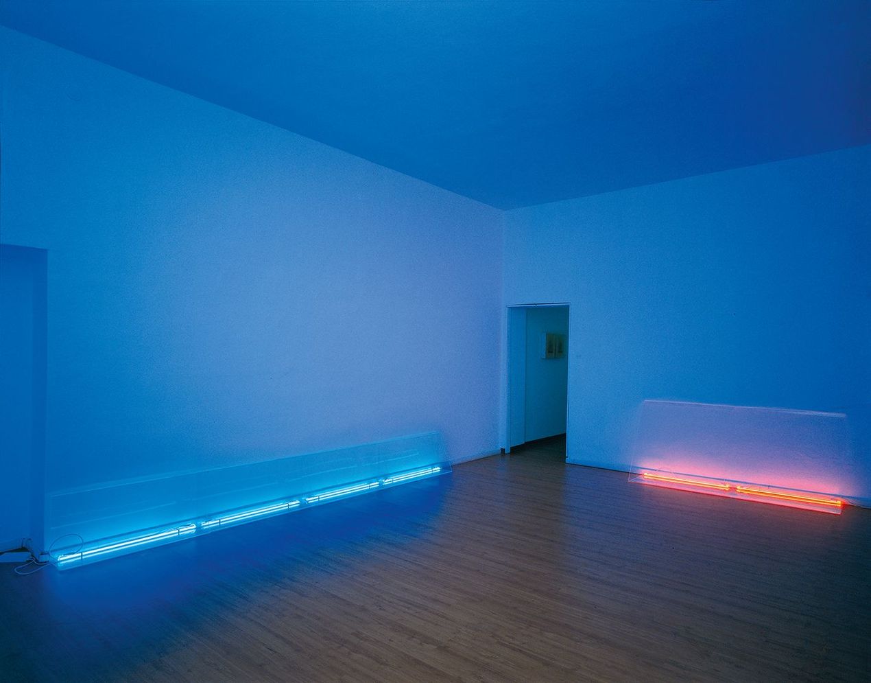 Sala espositiva minimalista con strisce LED blu e rosa lungo il pavimento e una porta sul retro.