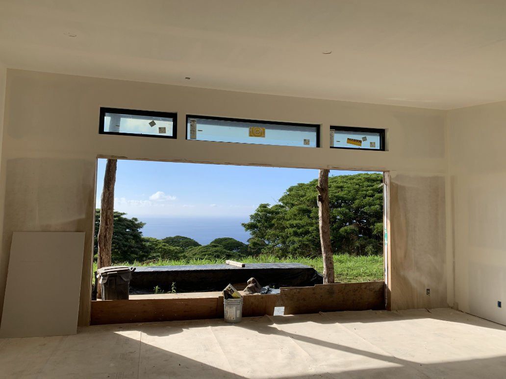 An empty room with a view of the ocean through a large window.