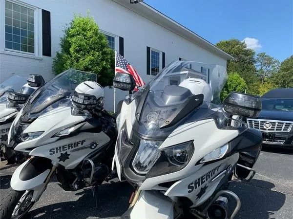 Two white Sherpa motorcycles parked outside a building on a sunny day