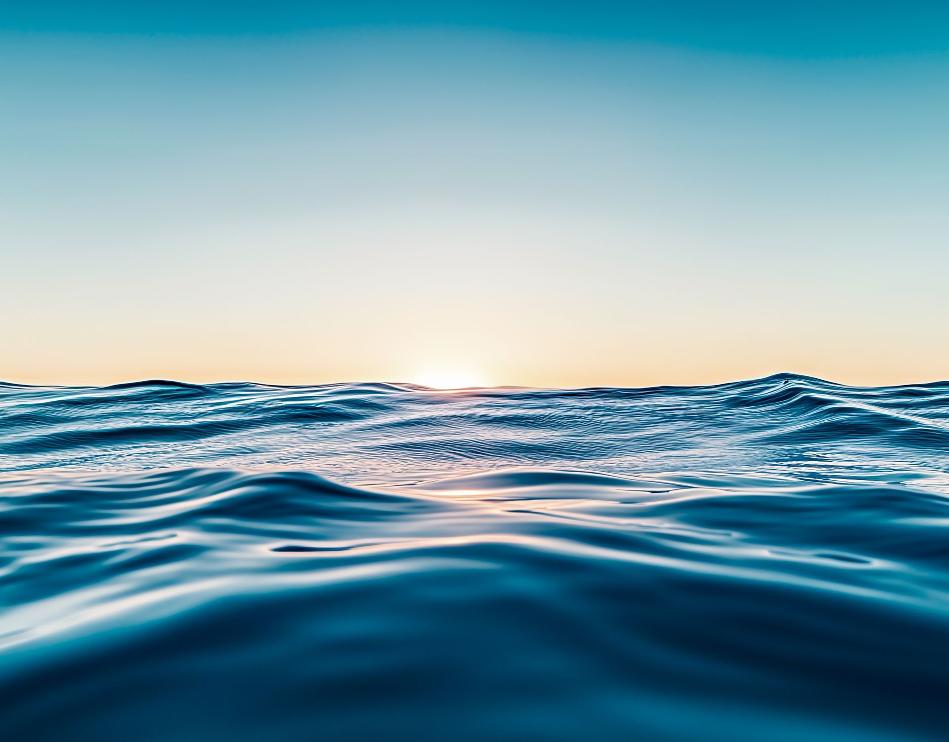 Sunlit ocean waves under a clear blue sky at sunrise