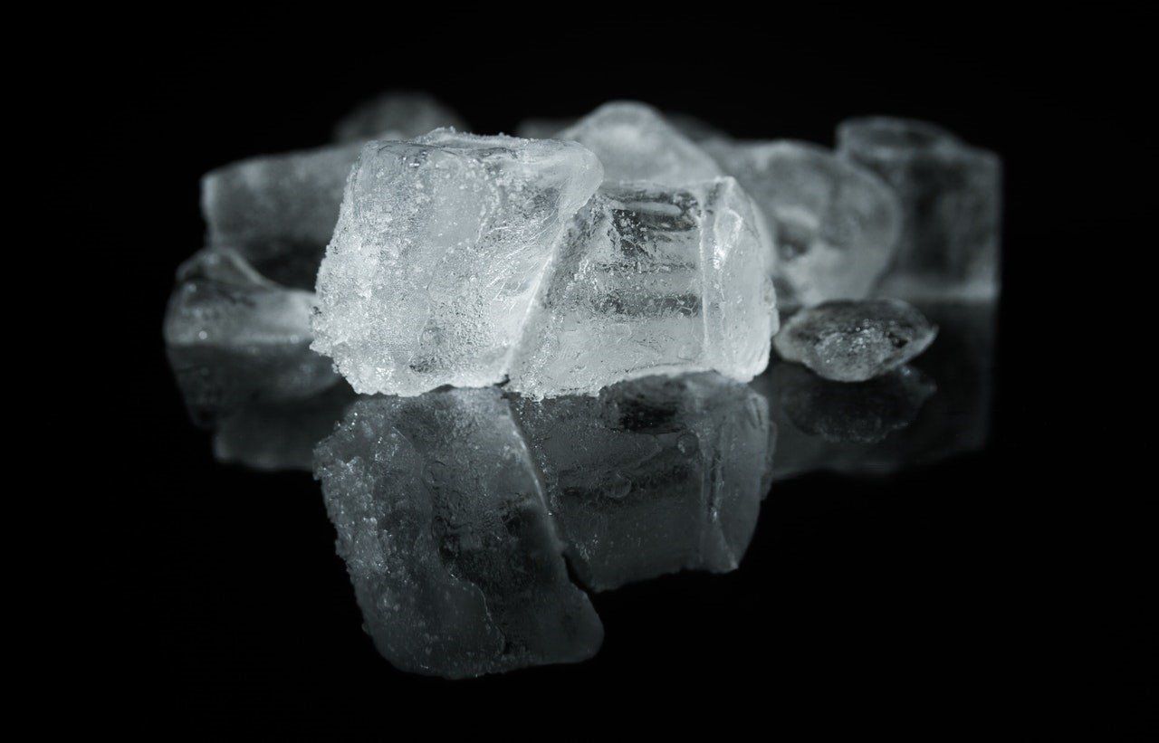 Translucent ice cubes on a black background, reflecting light.