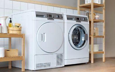 Modern laundry room with a white washer and dryer, wooden shelving, and woven storage baskets