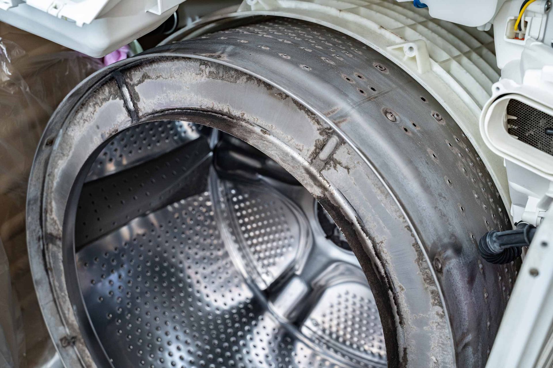Open washing machine drum with stainless steel interior and gray rubber gasket