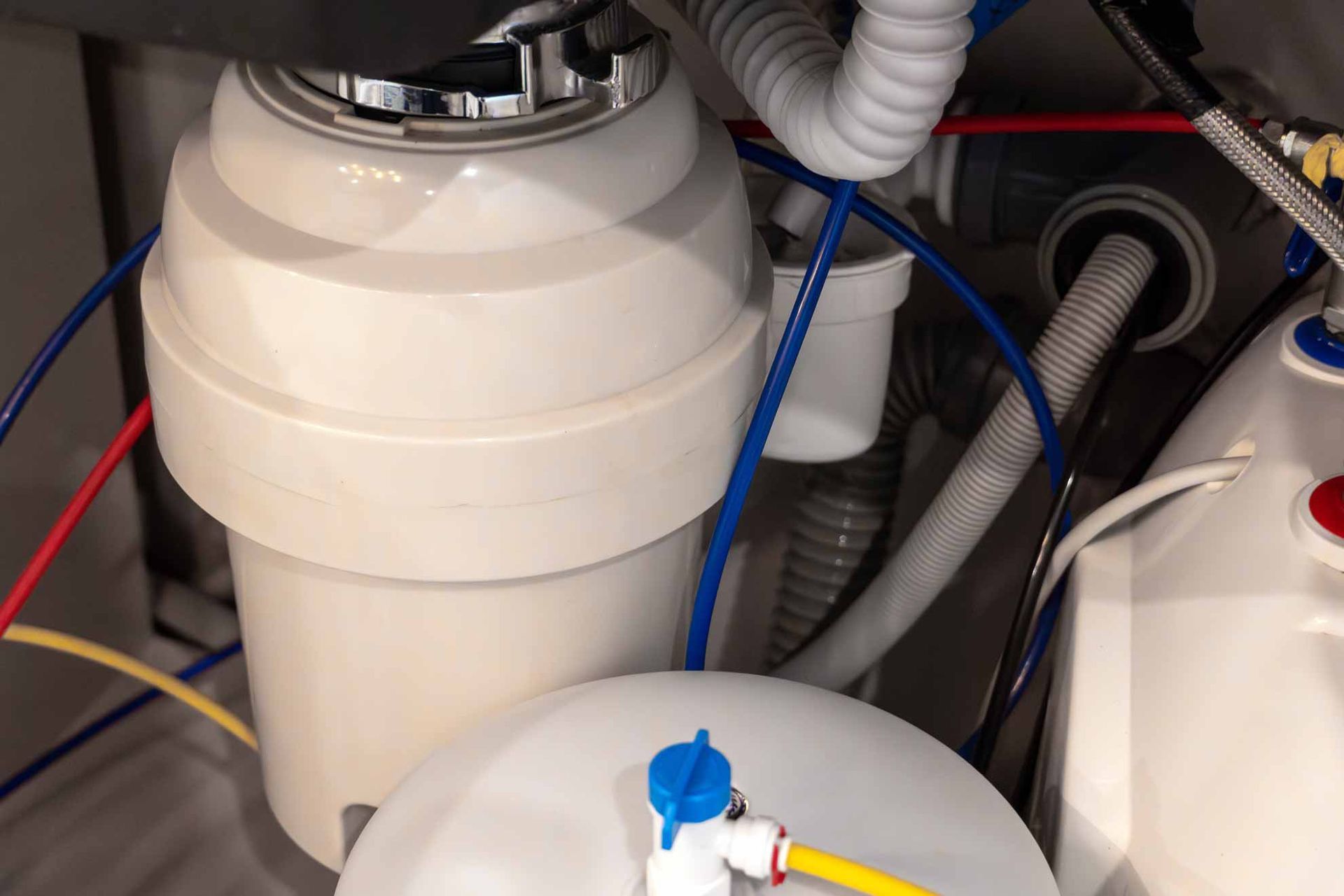 Close-up of white plastic tanks with blue and red hoses in a mechanical compartment