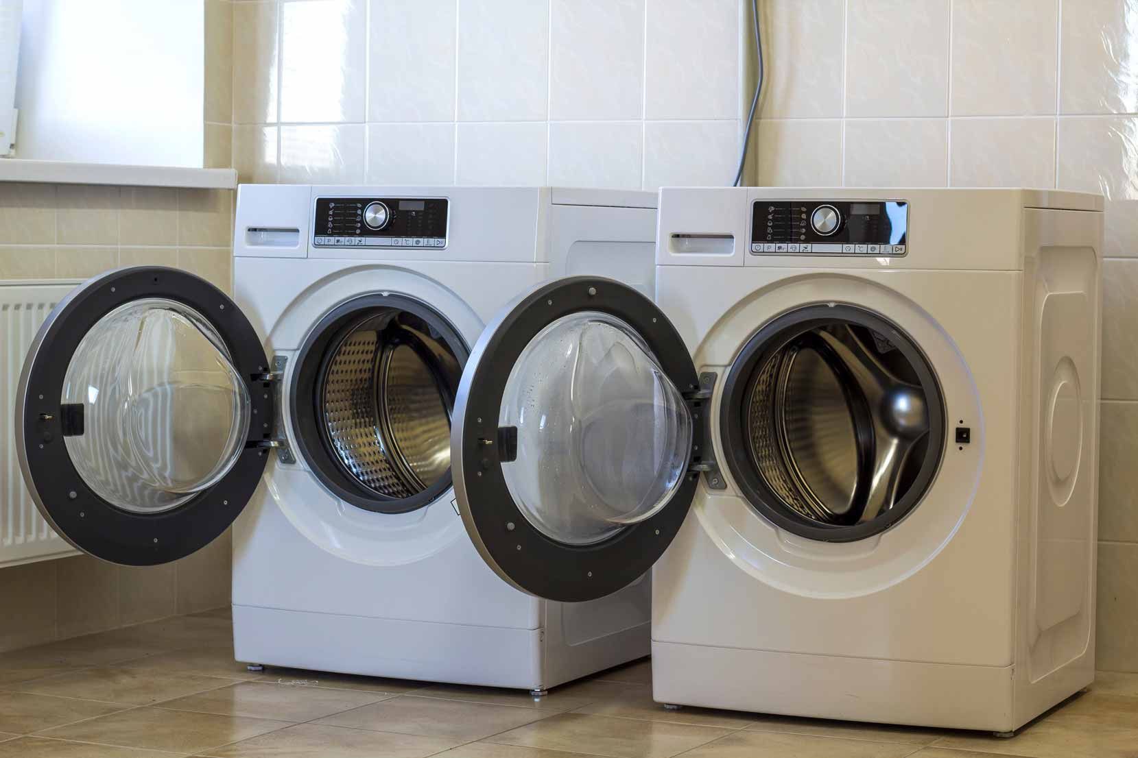 Two front-loading washing machines with open doors in a laundry room