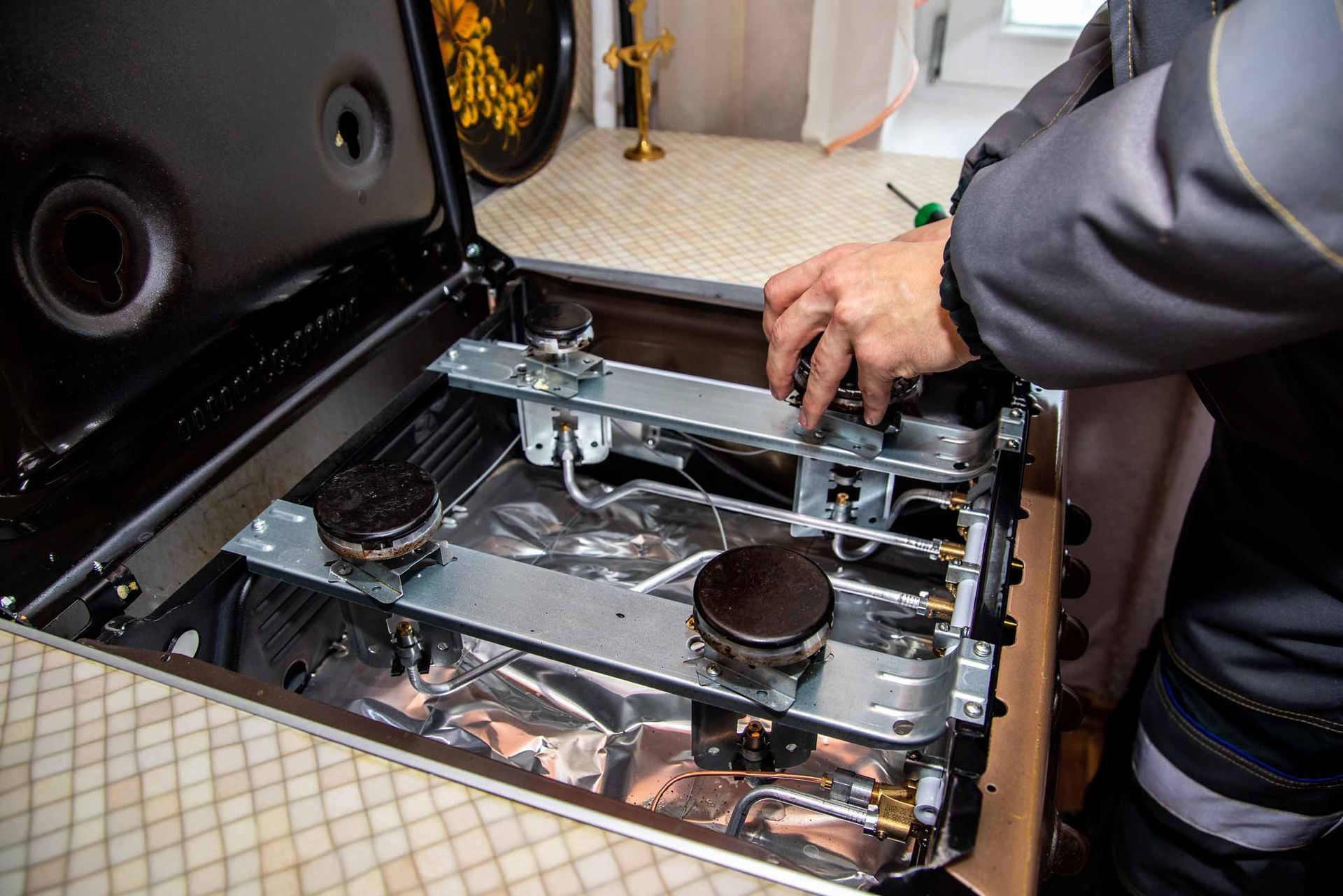 Person adjusting a portable gas stove with two burners in a kitchen sink area