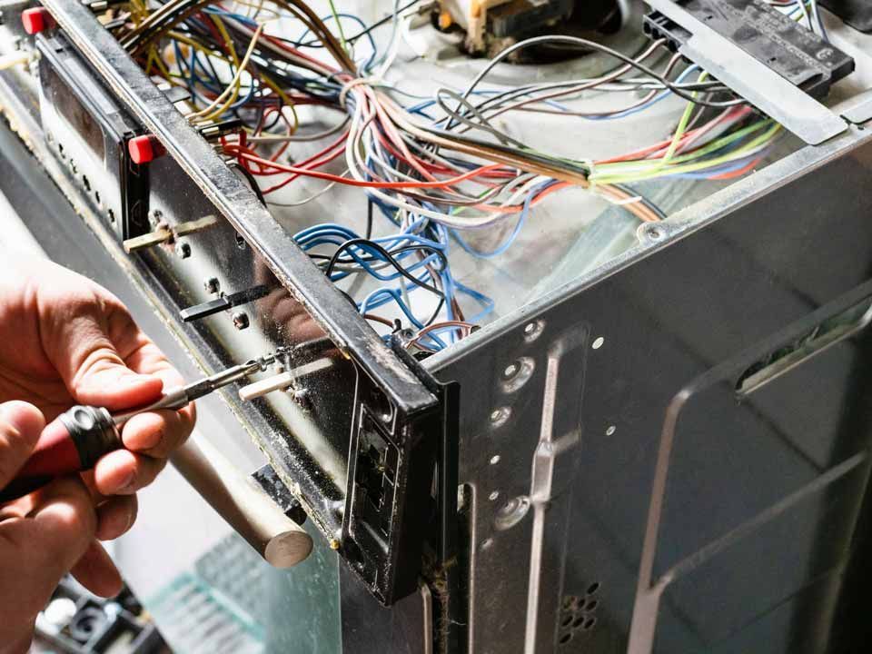 Technician using a screwdriver to repair wiring inside an open computer/server chassis