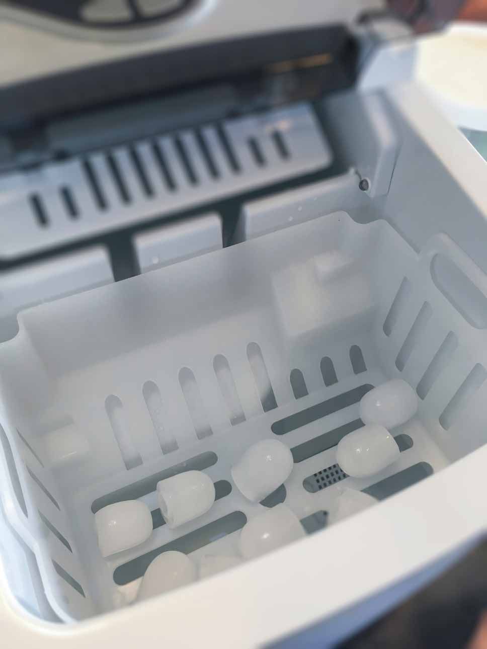 White plastic basket with several white capsules inside a machine tray