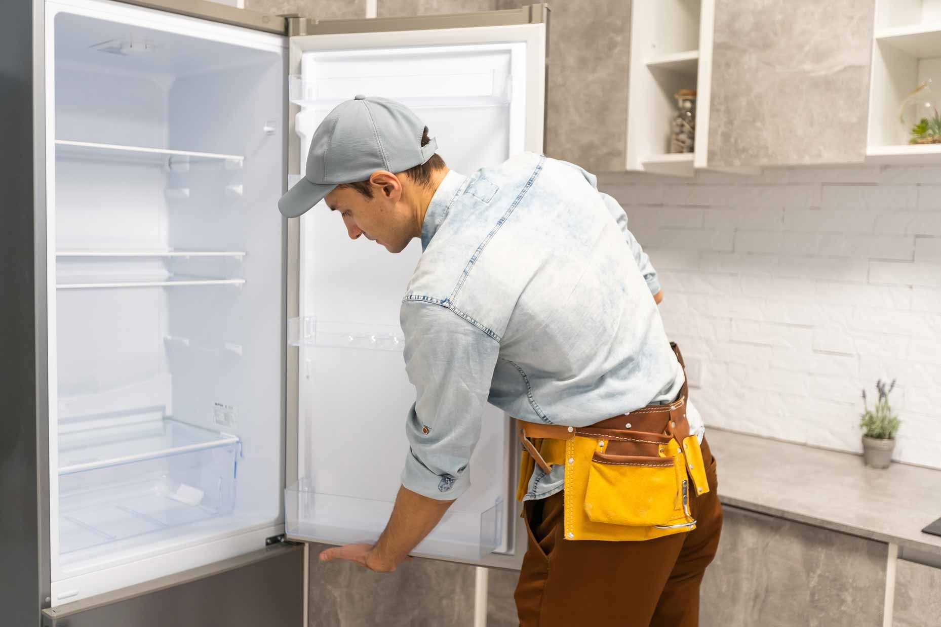Technician inspecting an open refrigerator in a bright kitchen