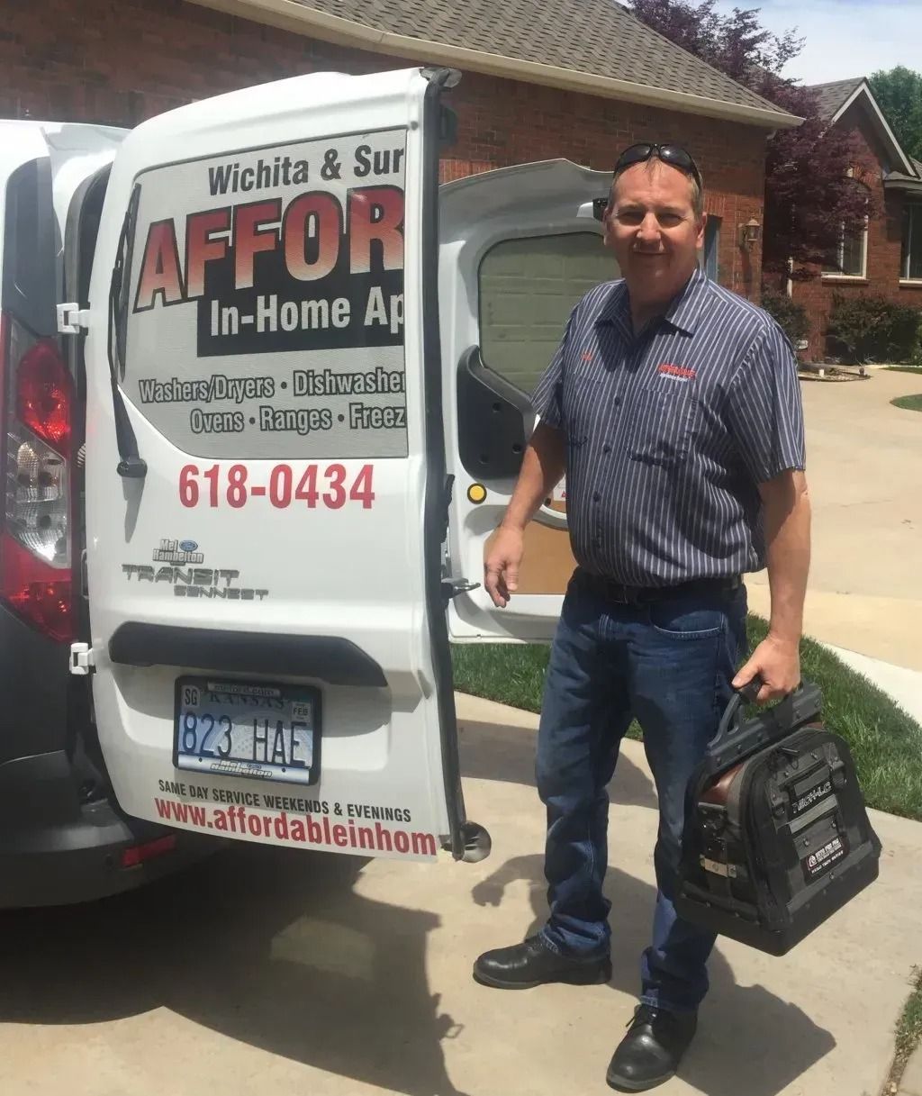 Man standing beside a service van with company signage, holding a black bag in a driveway.