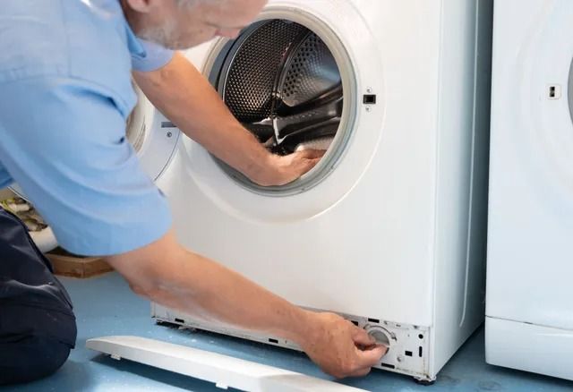 Technician repairing a front-load dryer with the door open