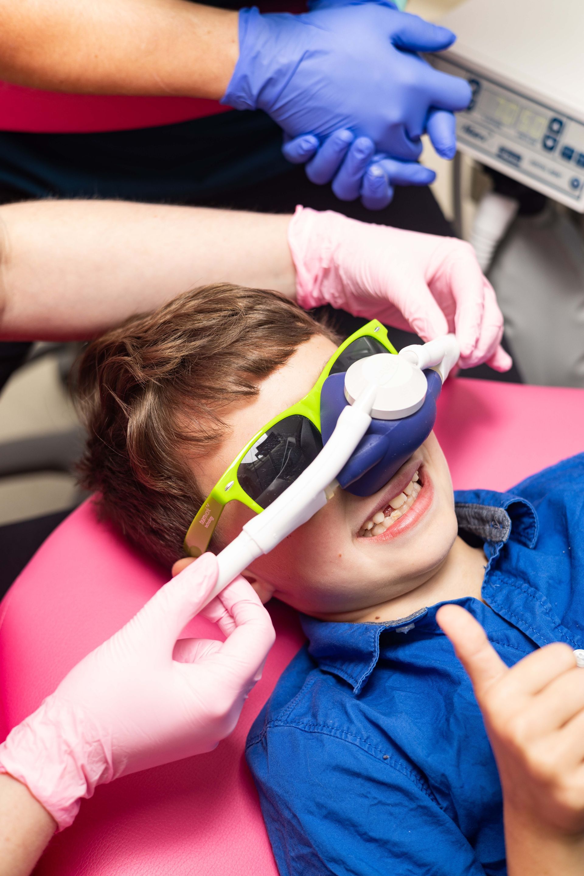 A woman in pink gloves using sedation on a child.