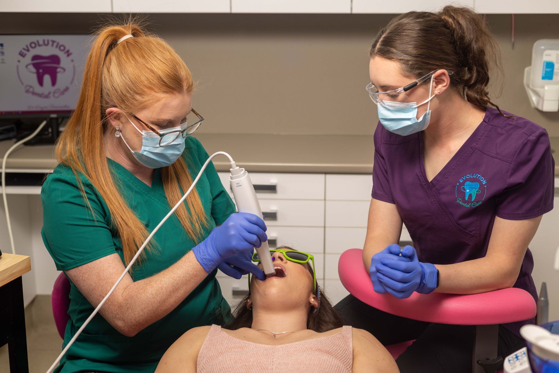 Two female dentists are examining a patient's teeth in a dental office.