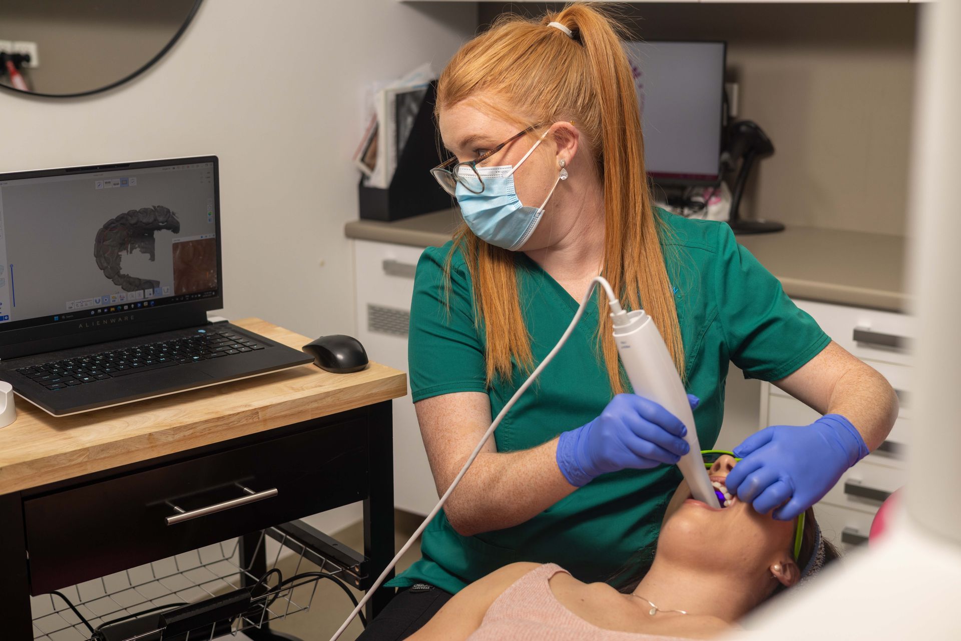 A woman wearing a mask and gloves is using a machine on a patient's face.