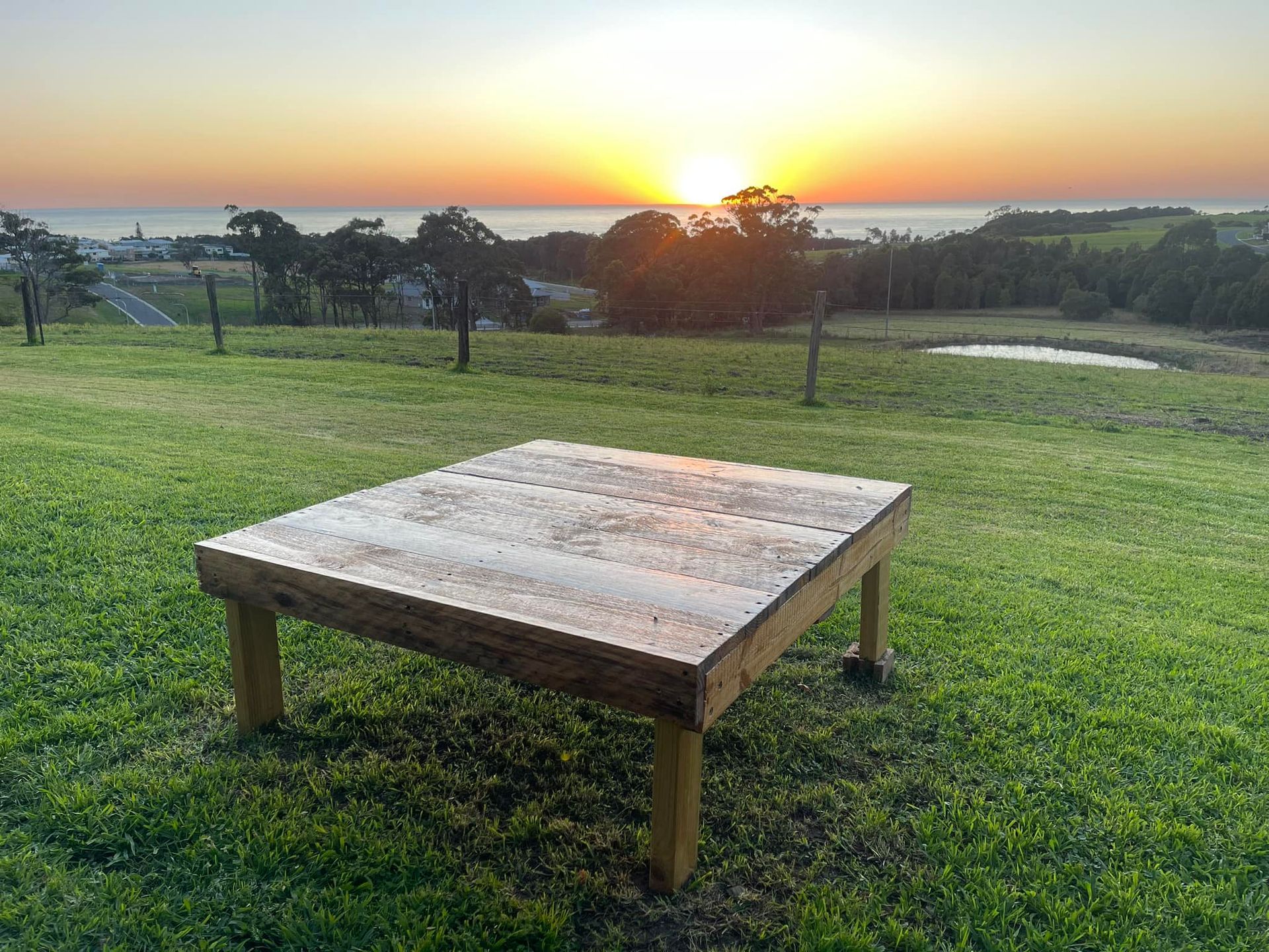 Wooden Square Table on Grassy Hill Overlooking Ocean at Sunset — Coastal Slashing & Mowing Services In Taree, NSW