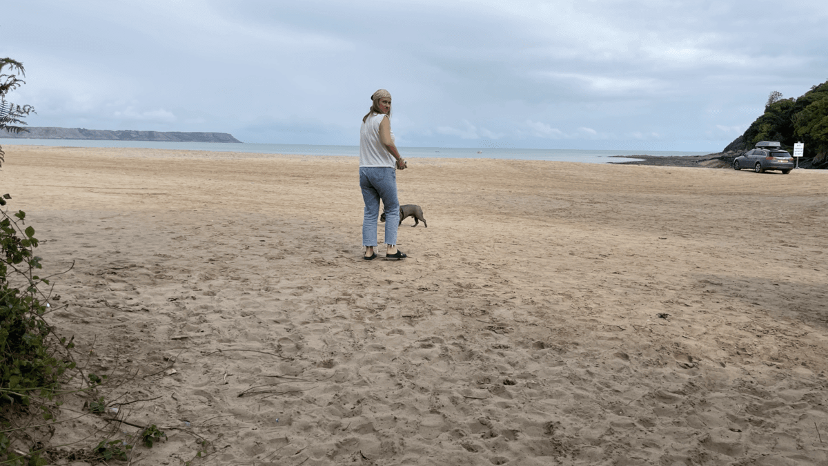 Kez walking Frank the Frenchie on a beach.