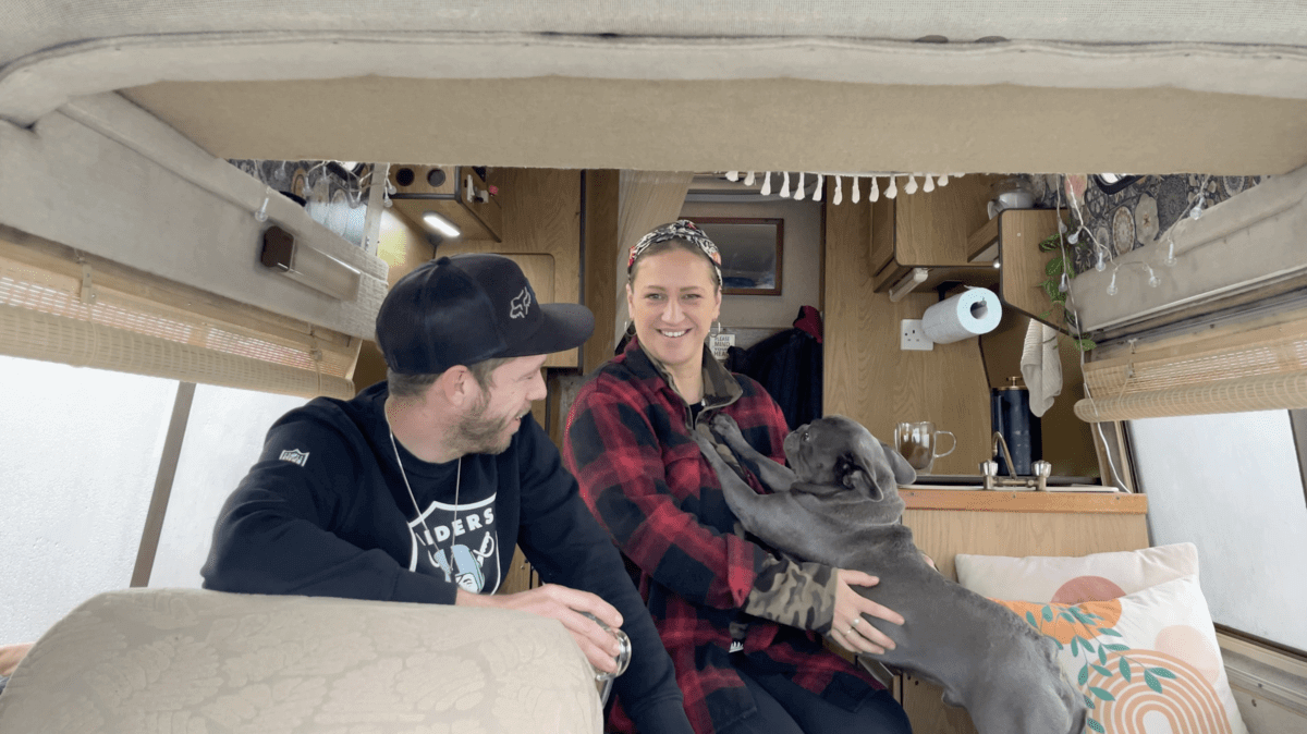 Trist and Kez are sitting in a van holding a dog.
