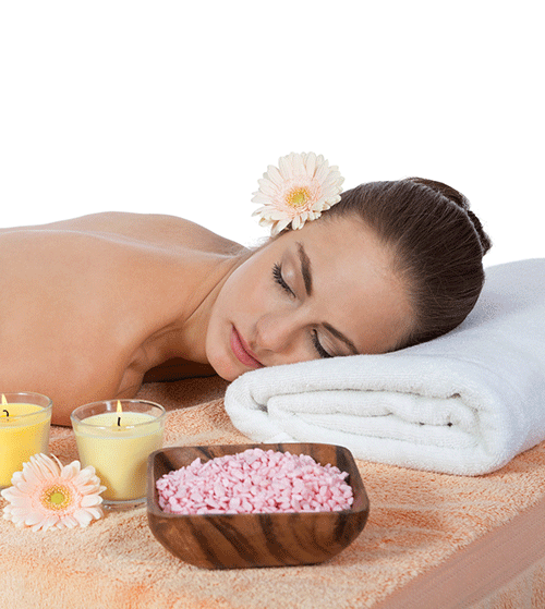 Eine Frau liegt in einem Spa mit Kerzen und Meersalz auf einem Handtuch.