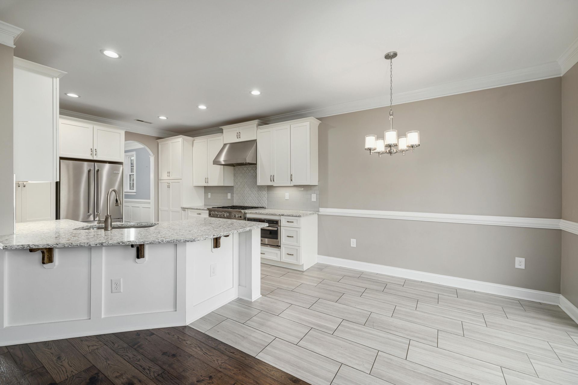 Modern kitchen with white cabinets, granite countertops, and light gray walls.