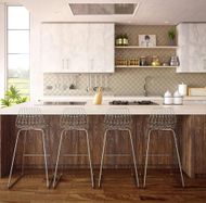 Modern kitchen with a wood island, four clear wire bar stools, and white cabinets.