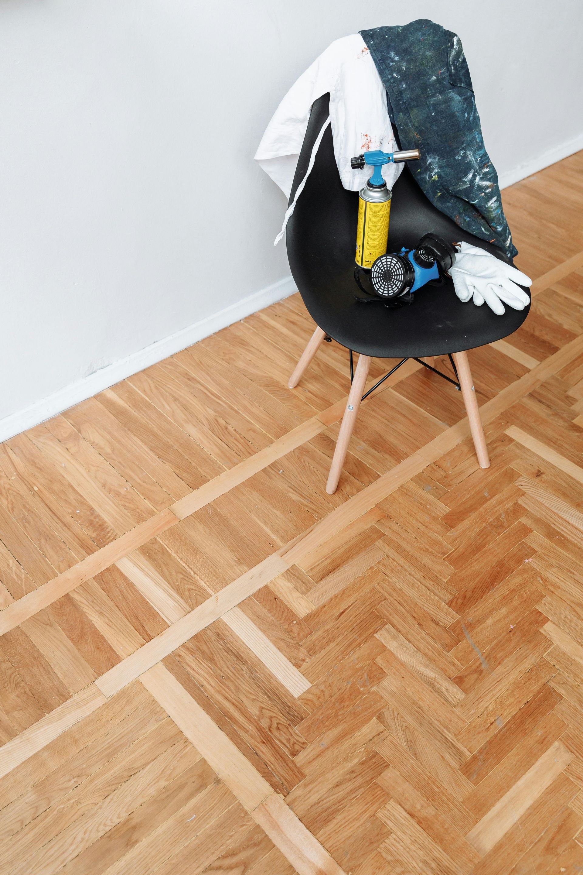 Chair with tools and work clothes on hardwood floor.