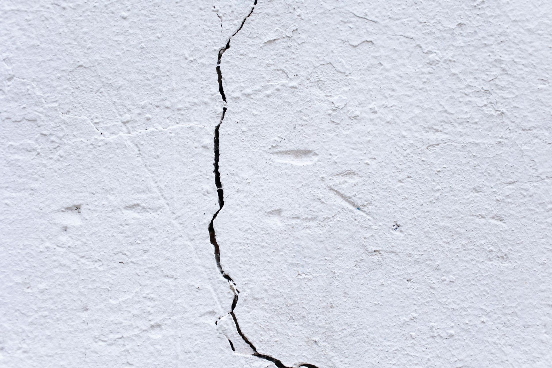 White painted wall with a vertical crack running down the center.