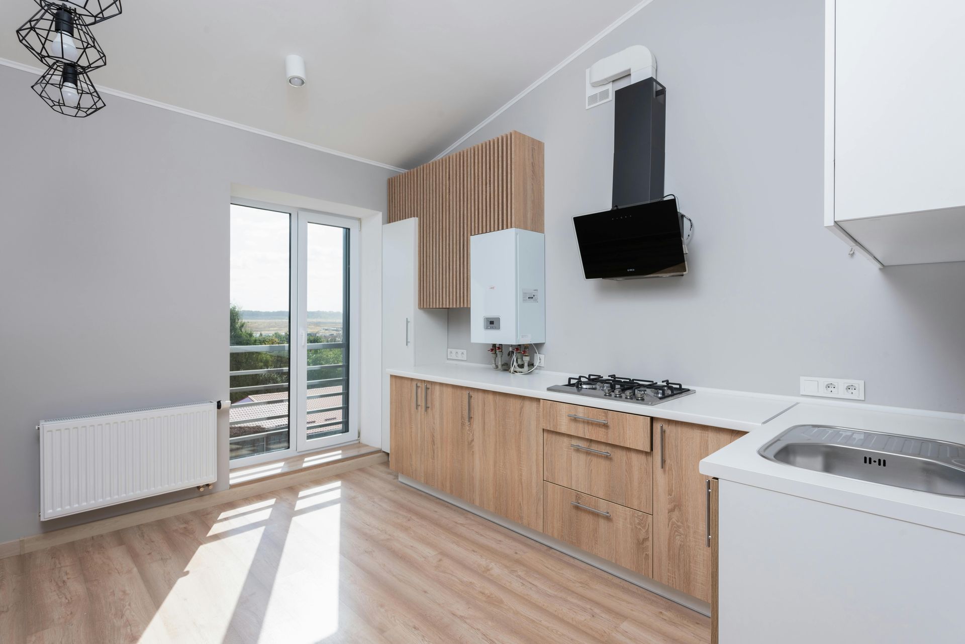 Kitchen with light wood cabinets, gray walls, and a sliding glass door.
