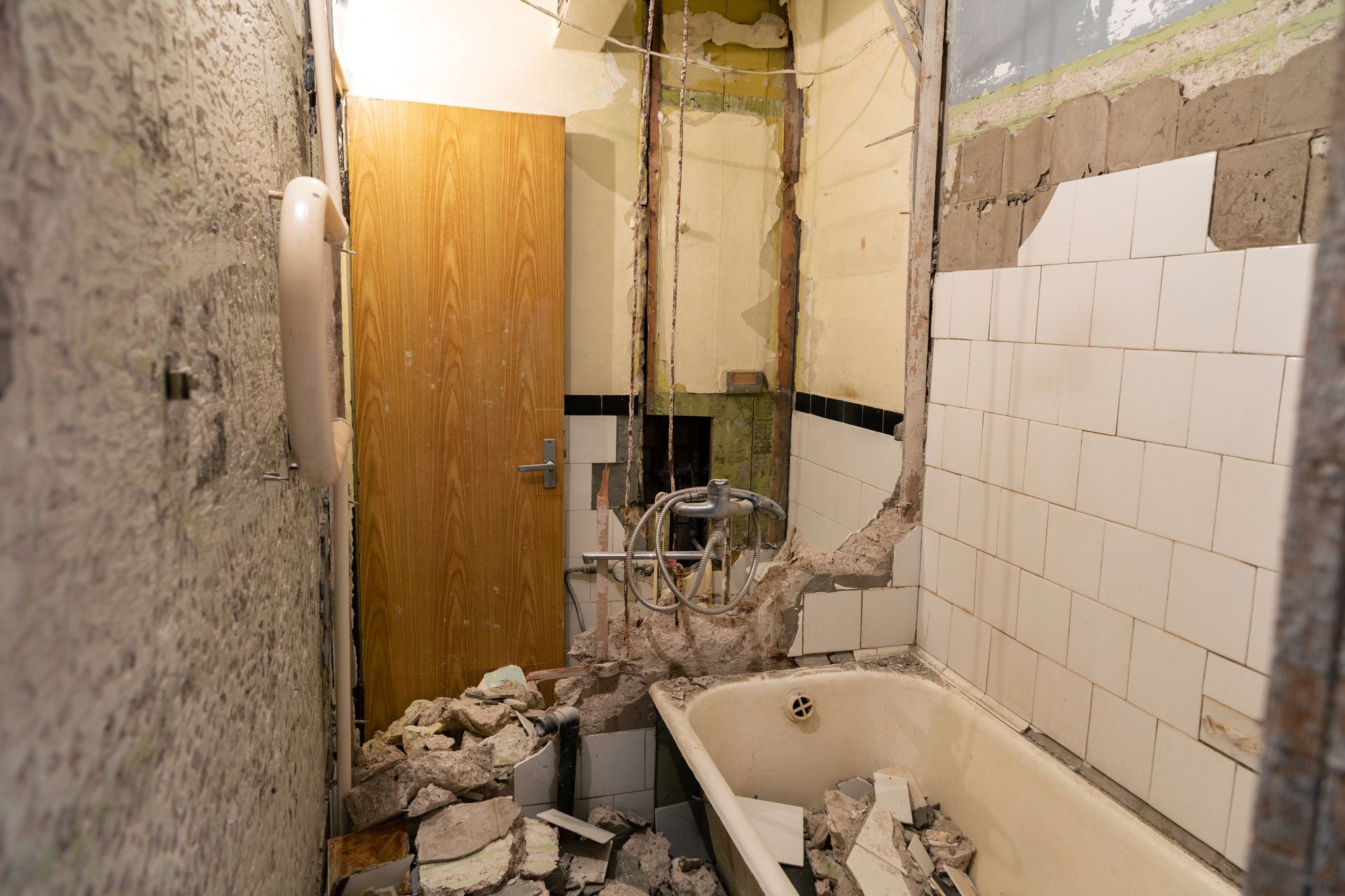 Bathroom with partially removed wall finishes and demolition debris
