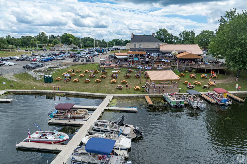 An aerial view of a lakeside restaurant with an outdoor seating area, grassy lawn, and a marina in Portage Lakes.