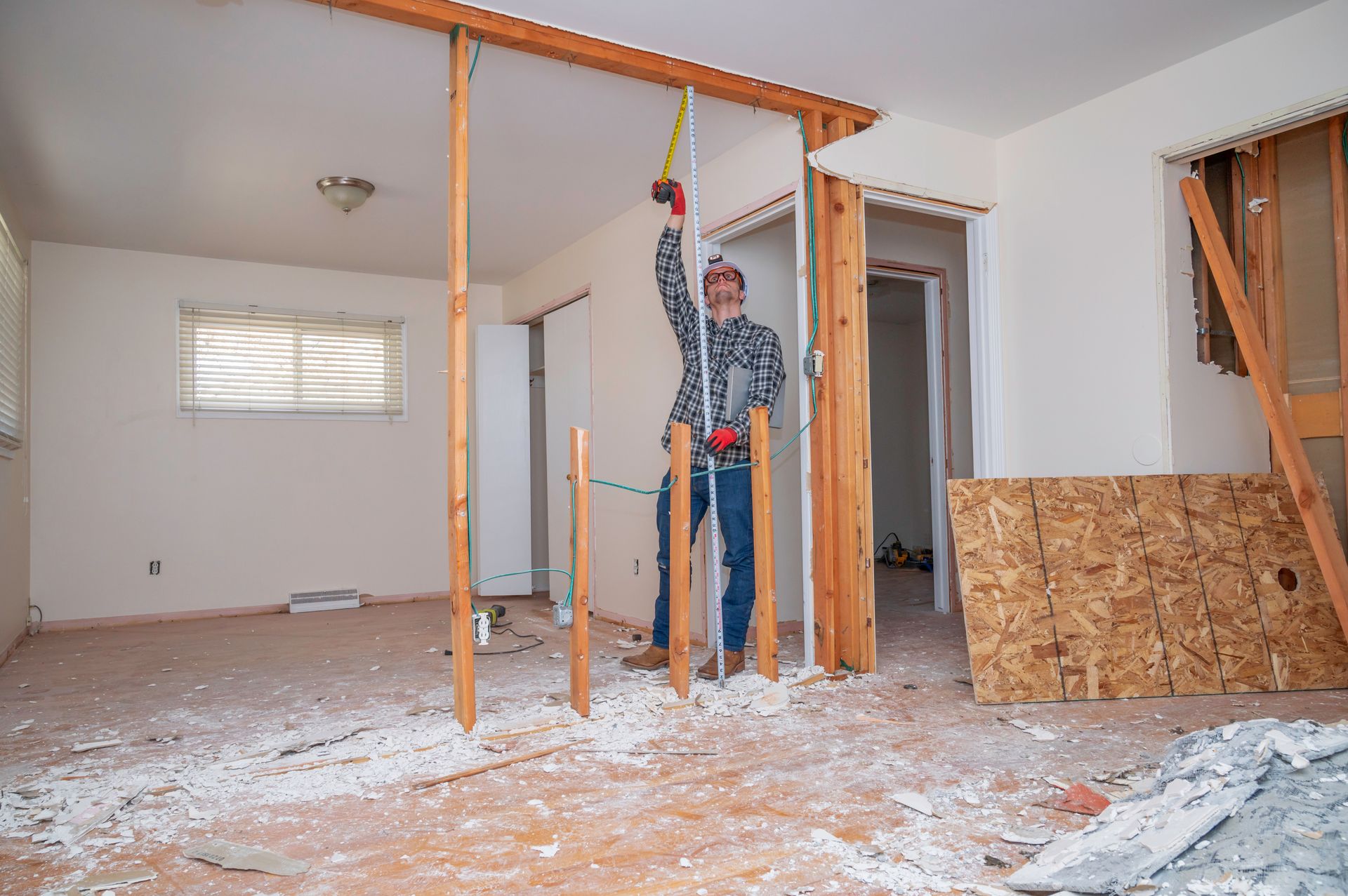 Worker removing interior wall material beside exposed studs