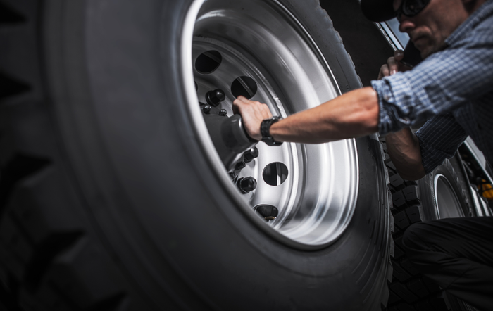 A man is changing a tire on a truck.