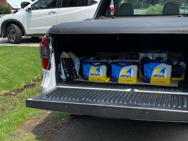 Unas manos enguantadas instalando una batería de coche en el compartimento del motor