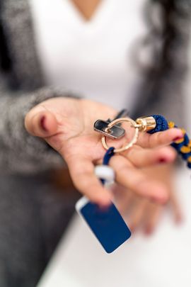 Hand holding a beaded bracelet with a blue tag, close-up on a blurred background